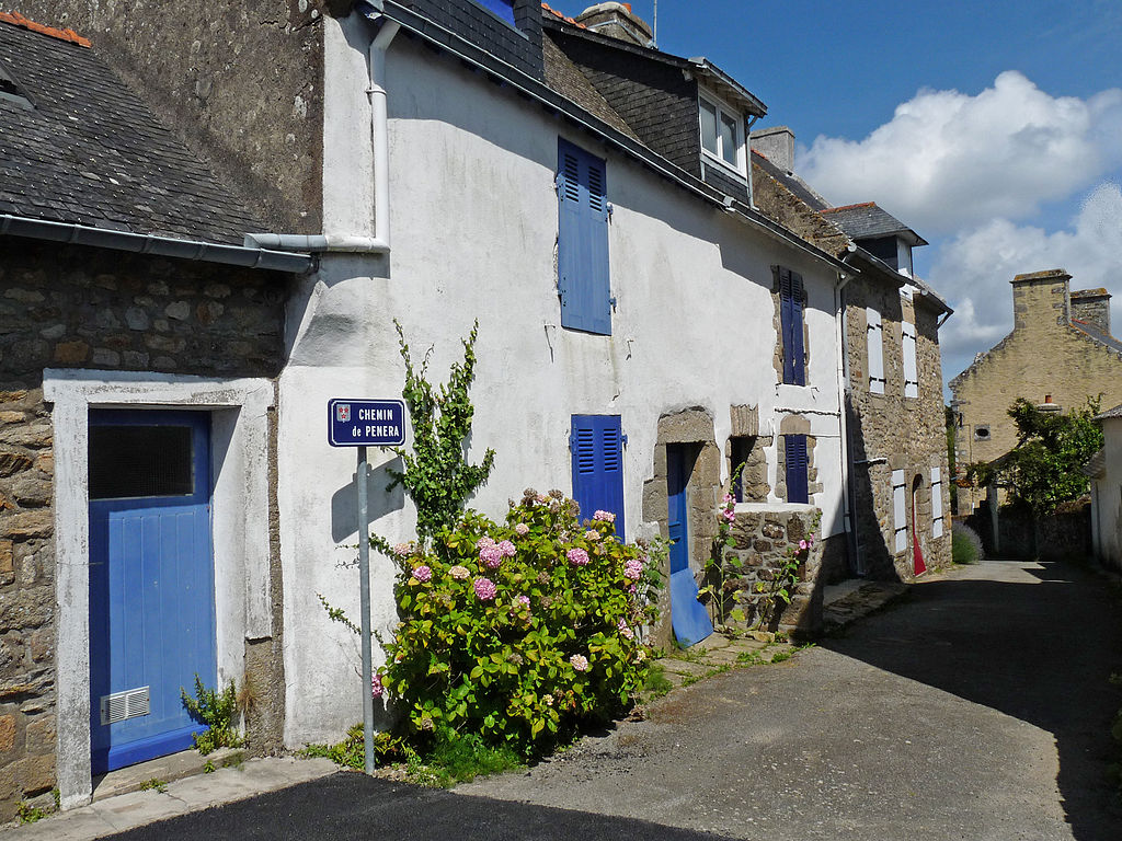 Una pequeña calle en Ile d'Art en las islas de Bretaña con un lado de la calle una pequeña casa blanca de dos plantas y plantas fuera