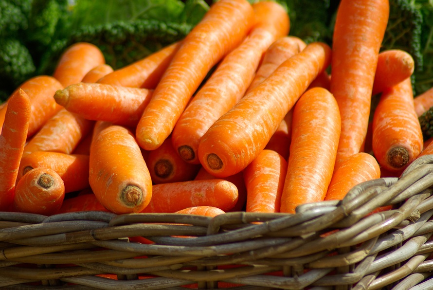 Una cesta de mimbre llena de zanahorias de color naranja brillante