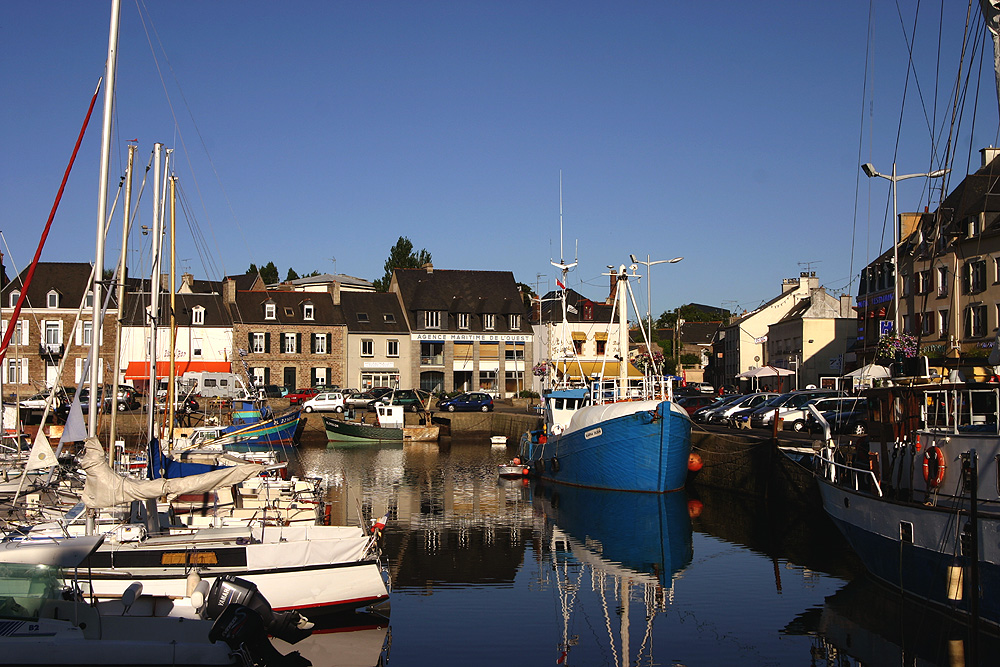 Puerto pesquero de Paimpol con barcos de pesca en el puerto en primer plano y casas antiguas detrás y un yate a la izquierda