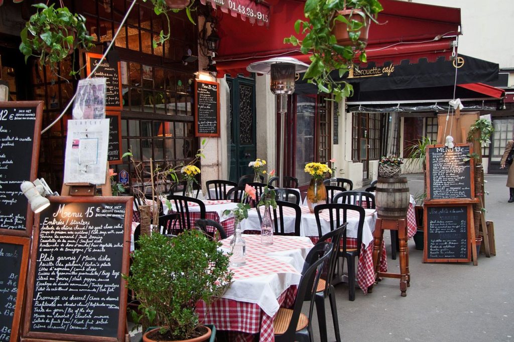 Restaurante en la rue Moufetard, terraza al aire libre de París con una mesa en la lista de un menú de 15 euros y mesas con manteles blancos y mucha vegetación