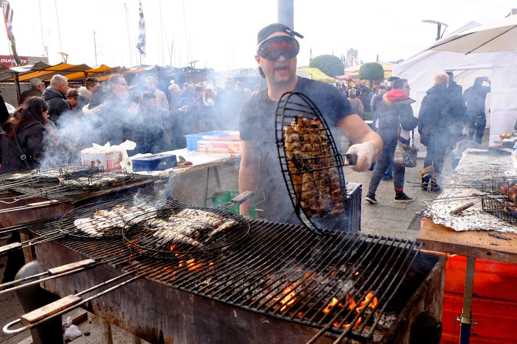 Festival del arenque de Dieppe con un hombre cocinando arenque en una parrilla sobre un fuego