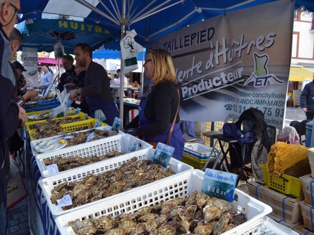 Puestos de venta de mariscos con mariscos en cajas de plástico y dos personas sirviéndolos