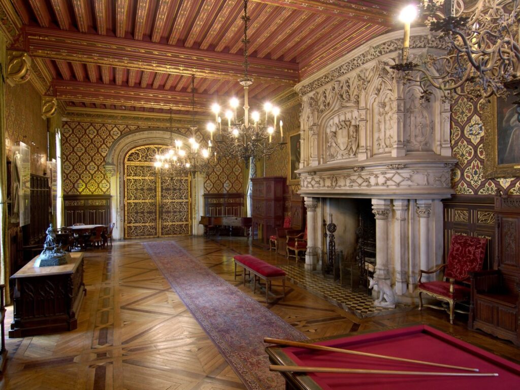 Gran recepción Château du Lude Renaissance Room con una enorme chimenea de mármol a la derecha, techo de madera decorado, candelabros y una larga galería