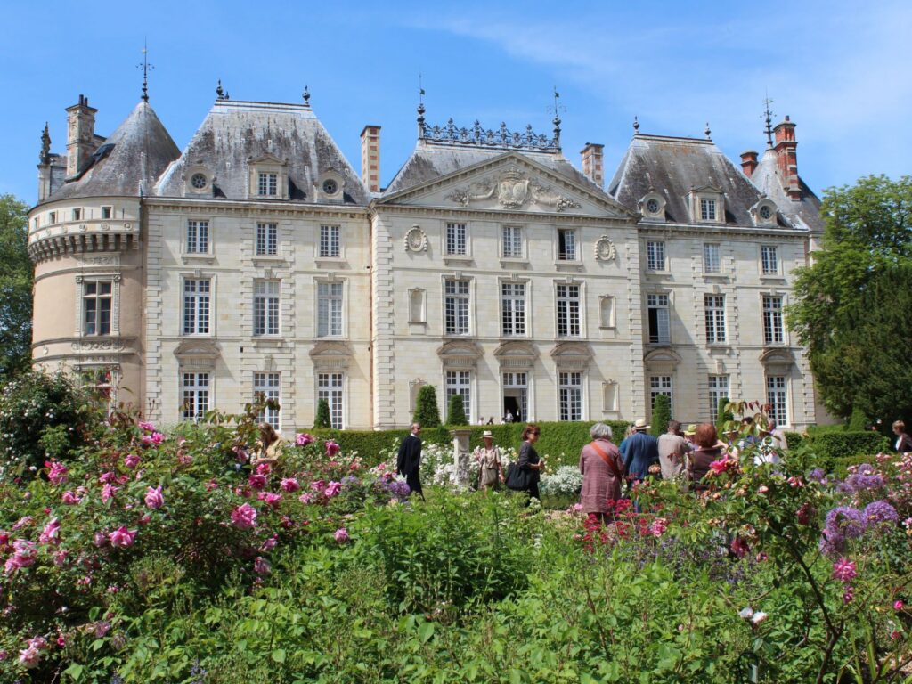 Château du Lude Loir Valley Rose Garden con gente entre rosales y arbustos verdes frente a una elegante fachada clásica del siglo XVIII