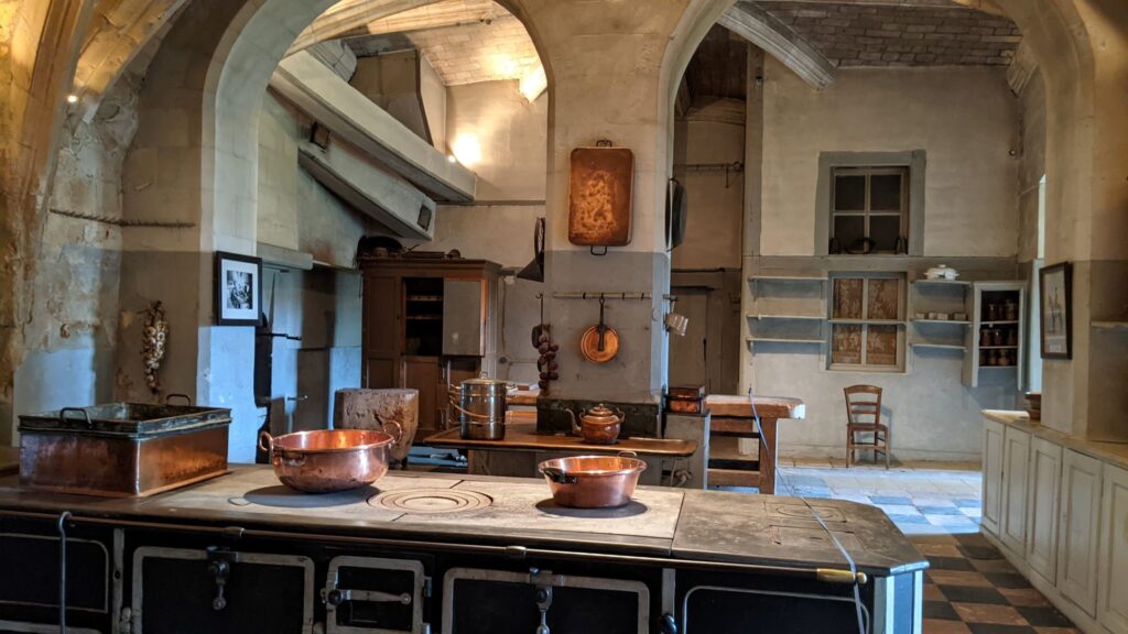 Château du Lude Cocinas del valle del Loir en una enorme sala abovedada con una estufa en el medio con ollas y sartenes, sartenes de cobre colgadas en la pared opuesta