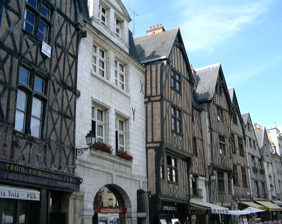 Casas de entramado de madera Tudor en blanco y negro en la calle con una piedra construida y otra en el medio. Cuatro plantas con hastiales.