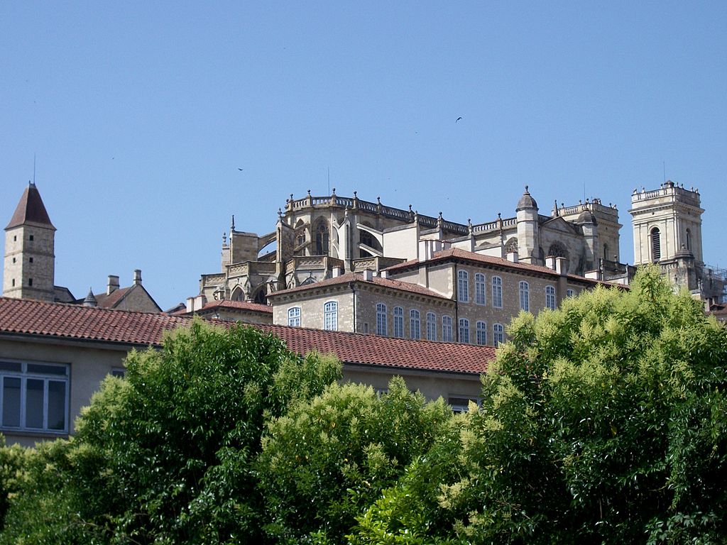 Auch, en el suroeste de Francia, mirando hacia una colina con una torre y una catedral desde el primer plano de los árboles