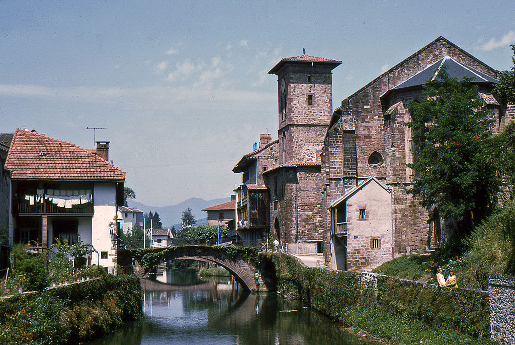 Saint Jean Pied de Port con un río y un antiguo puente de piedra que discurre entre dos orillas, con edificios a ambos lados en piedra antigua