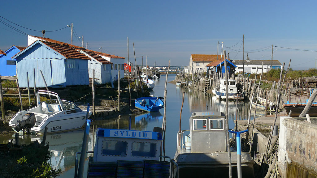 Isla Ile d'Oleron Francia mostrando un canal estrecho desde el mar que se ejecuta en la bahía de primer plano con barcos y casas a ambos lados de la isla