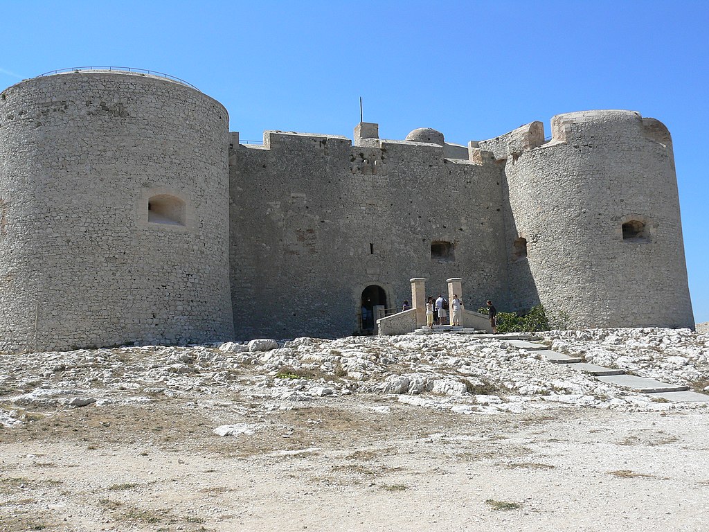 Las islas Chateau d'If de Francia que muestran la entrada a grandes muros de piedra fortificados flanqueados por dos torres redondas sobre roca