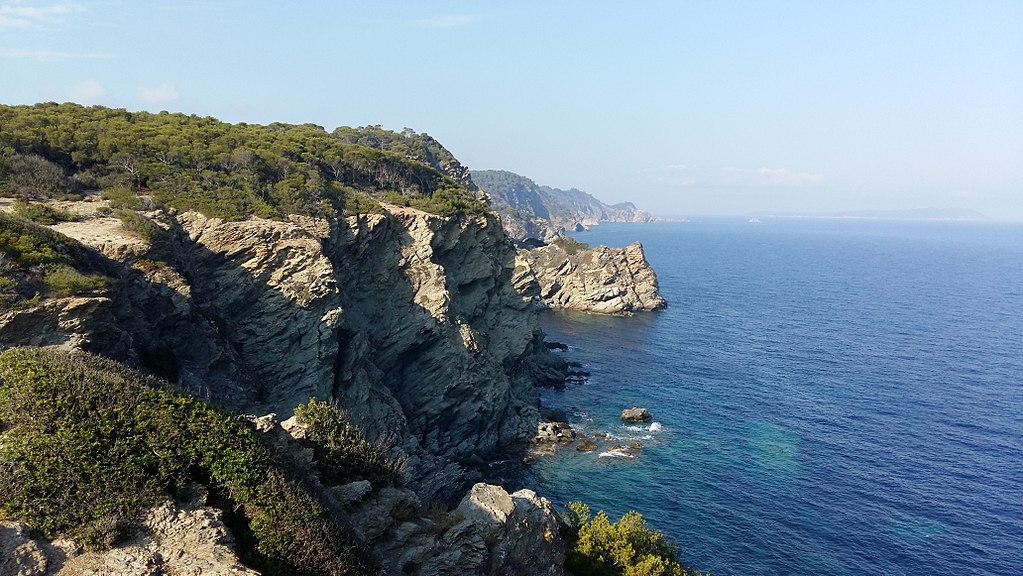 Ile de Porquerolles Francia desde la parte superior del promontorio mirando al mar a la derecha con una serie de afloramientos rocosos cubiertos de vegetación