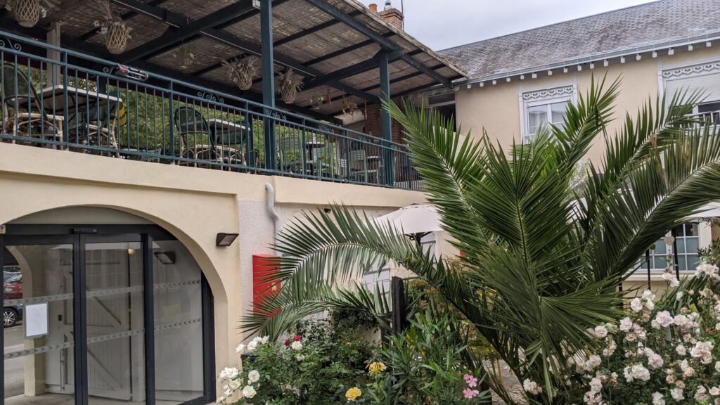 Hotel Le Relais du Loir mostrando el patio con flores y arbustos y una terraza sobre un muro sotrey