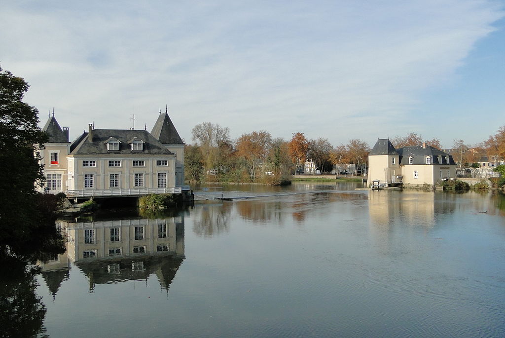 La Fleche en Glenloir en el río que muestra edificios clásicos por un lado y una torre cuadrada medieval por el otro con un telón de fondo de árboles de colores otoñales