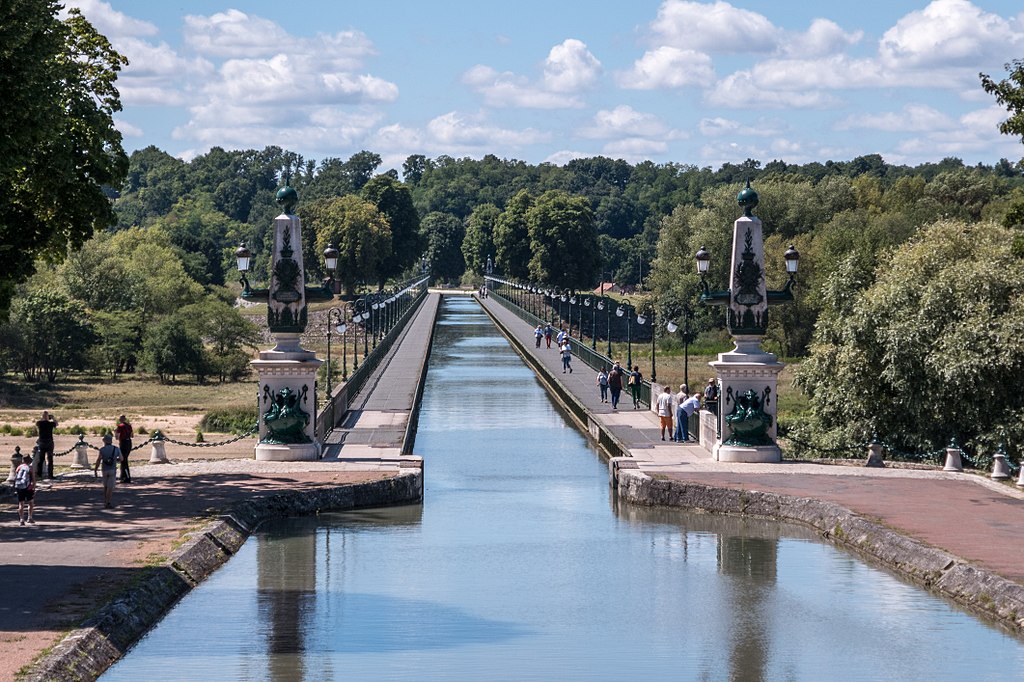 Mirando sobre el puente del Canal en Briare, Valle del Loira. Hierro fundido con grandes esculturas en la entrada del largo canal con aceras al lado