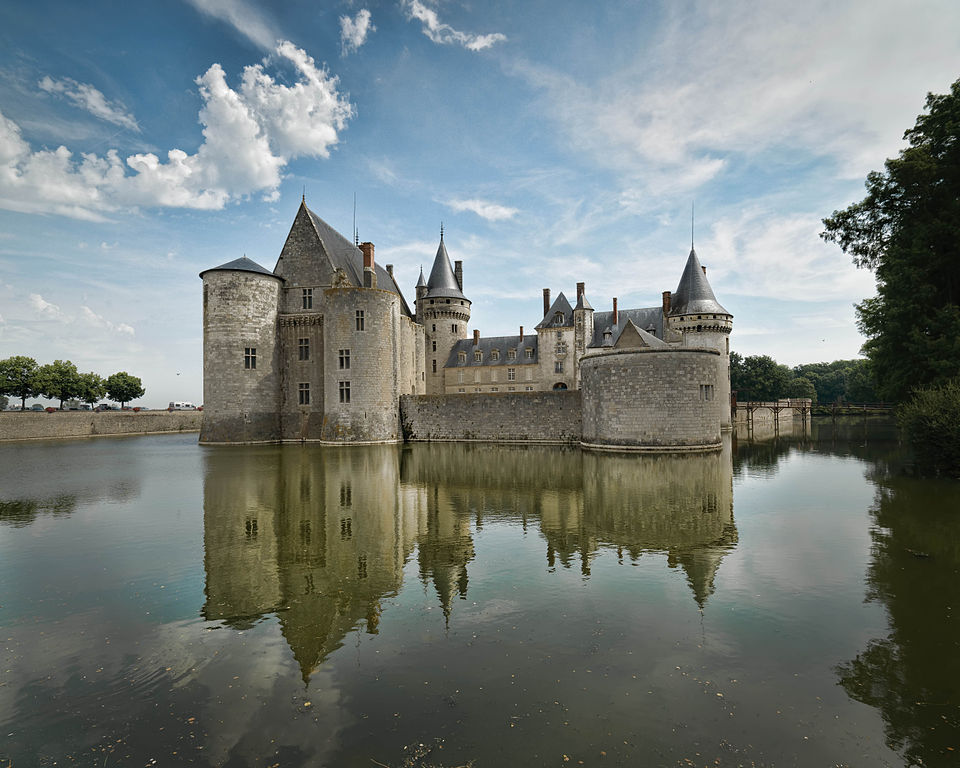 Chateau t Sully=-sur-Loire con castillos de cuento de hadas en aguas reflejadas, torres, cúpulas de cebolla, cielo con nubes blancas