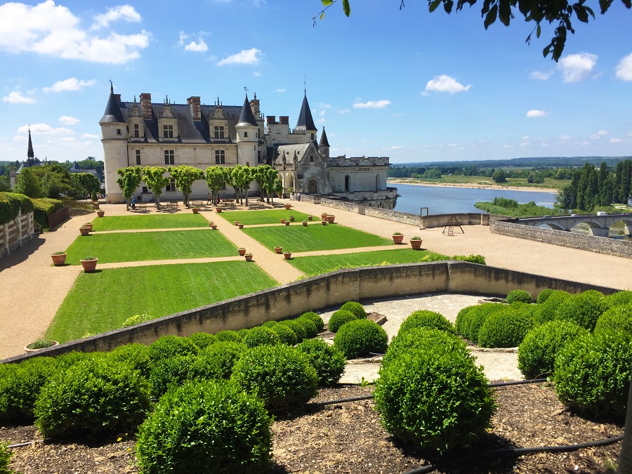 Chateau amboise, piedras blancas con cúpulas de cebolla y motivos y macizos de flores en el frente y el río Loira debajo a la derecha