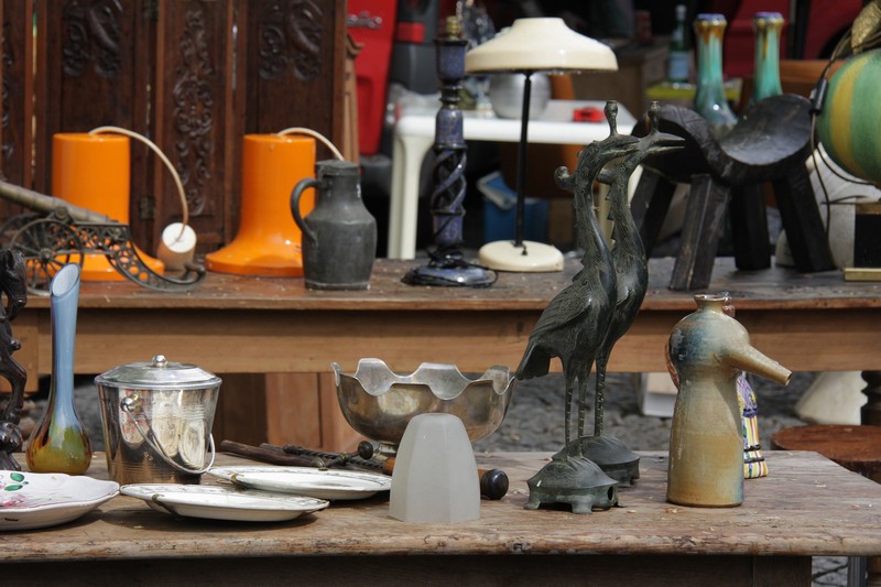 Rederie en Amiens con un puesto con estantes de varias antigüedades, desde una lámpara vieja hasta botas de color naranja carmesí, escultura de pájaro