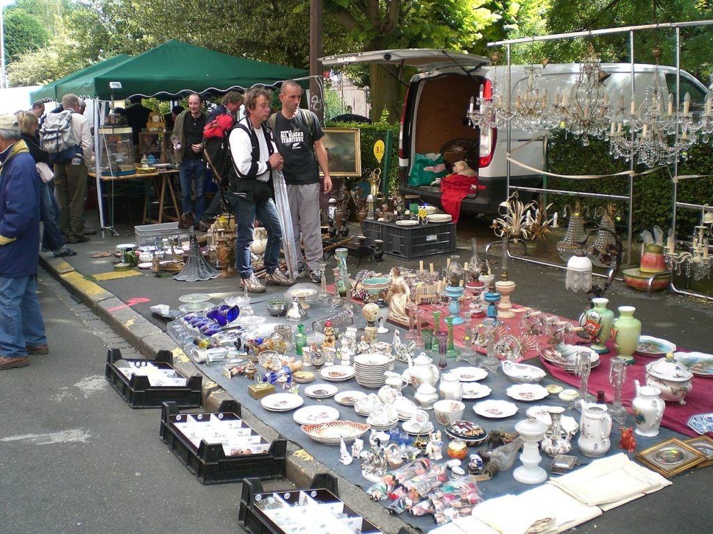 Lille Braderie, un mercadillo en Little con una carga de porcelana en el suelo sobre una lona, ​​cajas delante y gente mirándola