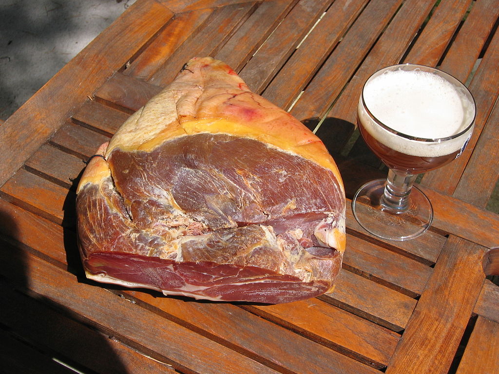 Jamón de las Ardenas francesas, con una mesa exterior con una gran pata de jamón y un vaso de cerveza