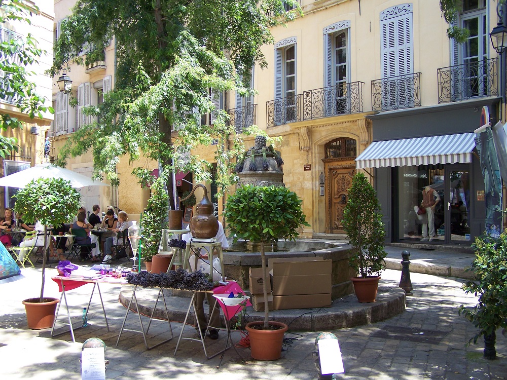 Una plaza sombreada con una fuente, casas de roble y cafés en Aix-en-Provence