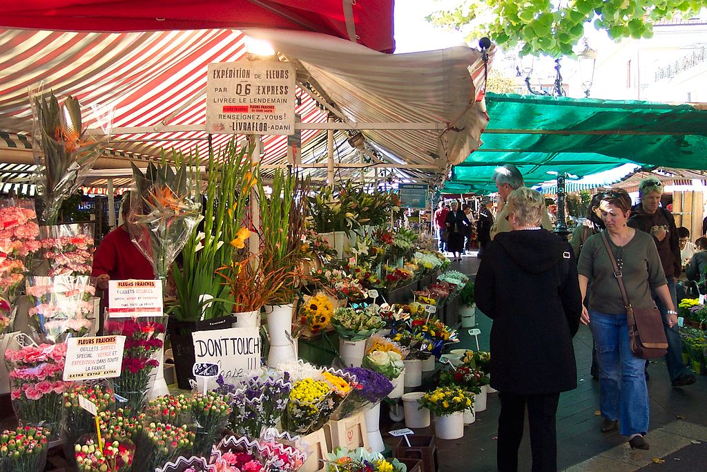 Mercado de Cours Saleya ofreciendo puestos de flores con una mujer en el medio