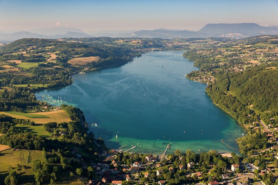 Vista aérea del lago Paladru. Un enorme lago que se extiende lejos con la ciudad al frente y las orillas del río con ciudades, caminos, colinas