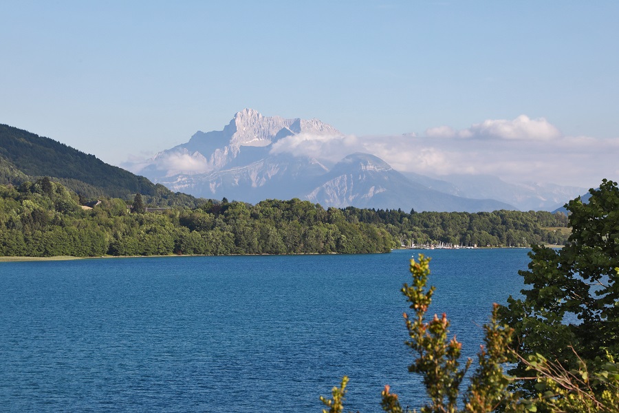 Las aguas azules de Loch Laffrey en primer plano con las verdes laderas y los picos nevados de Vercors al fondo