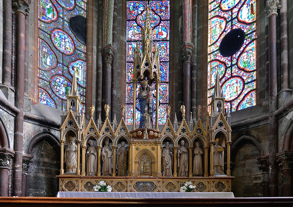 Una capilla lateral en la Catedral de Saint Julien en Le Mans que muestra un tríptico en el altar con vidrieras detrás