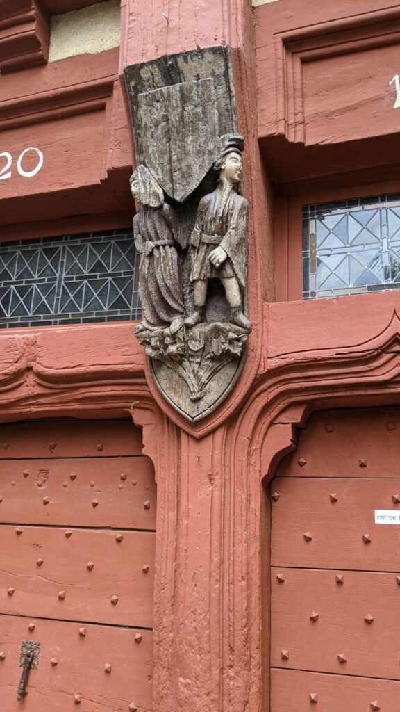 Dos figuras de madera en una casa antigua en Le Mans que muestran a un hombre orinando