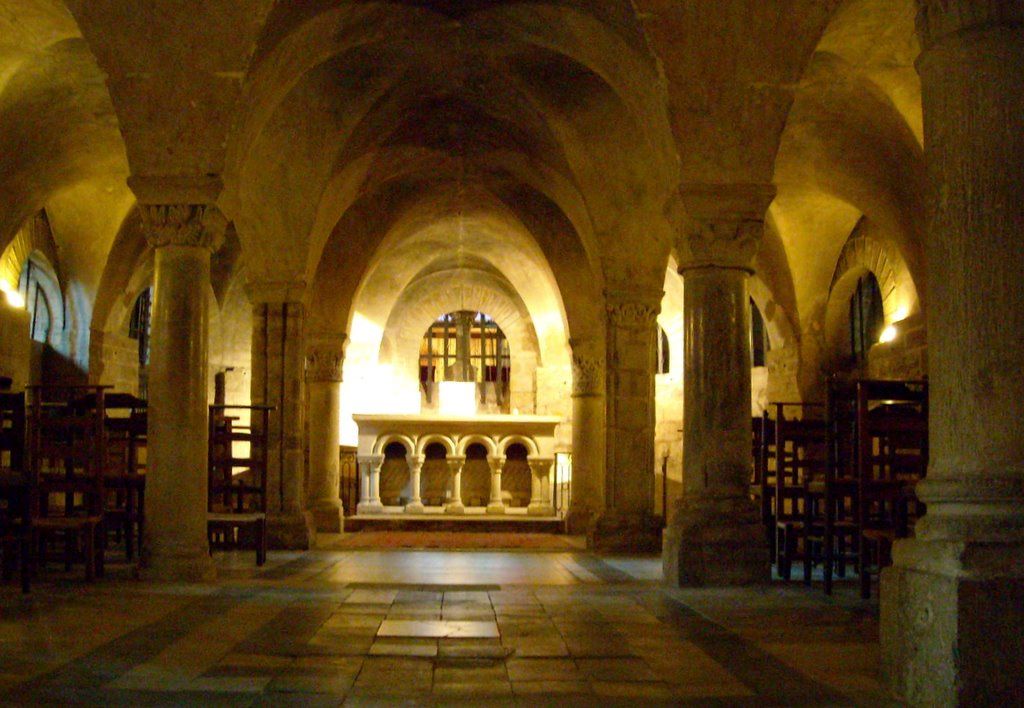 Cripta de Notre-Dame de la Couture Le Mans con enormes arcos románicos y un altar iluminado al final