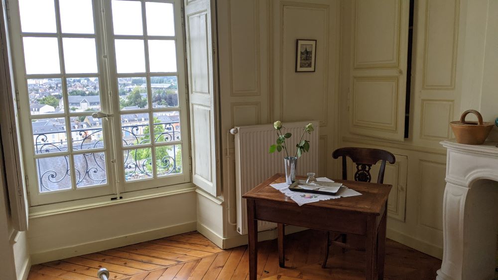 con una habitación de hombre con pisos de madera, ventanas de cuerpo entero, escritorio antiguo y decoración tradicional con vista al río. Cama y desayuno