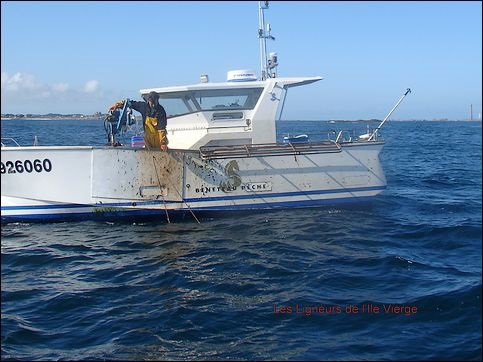 Un pequeño barco de pesca en el mar azul con un hombre desembarcando pescado