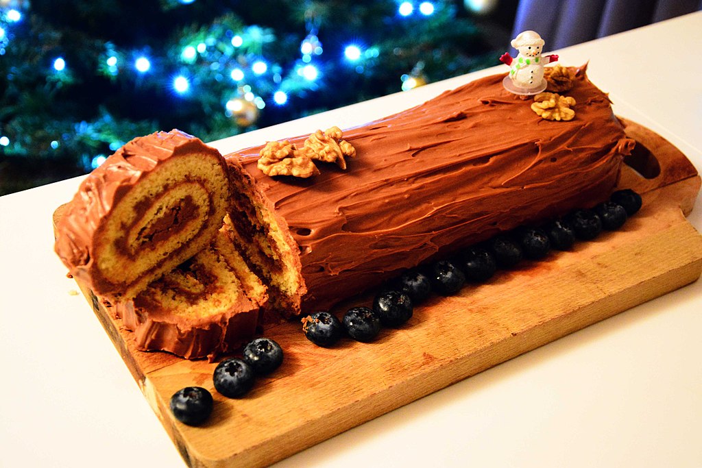 Pastel navideño francés Bûche de Noël con un bizcocho envuelto en chocolate en forma de tronco con dos rebanadas cortadas en el extremo visibles en el interior