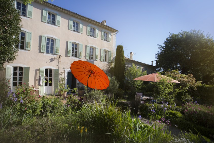 bed and breakfast la bastide en el jardín de Antibes con una casa al fondo y una sombrilla roja