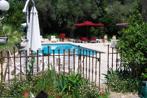 Cama y desayuno L'Air du Temps en Juan les pins vista de la piscina con sombrillas y sillas a través de la puerta de hierro