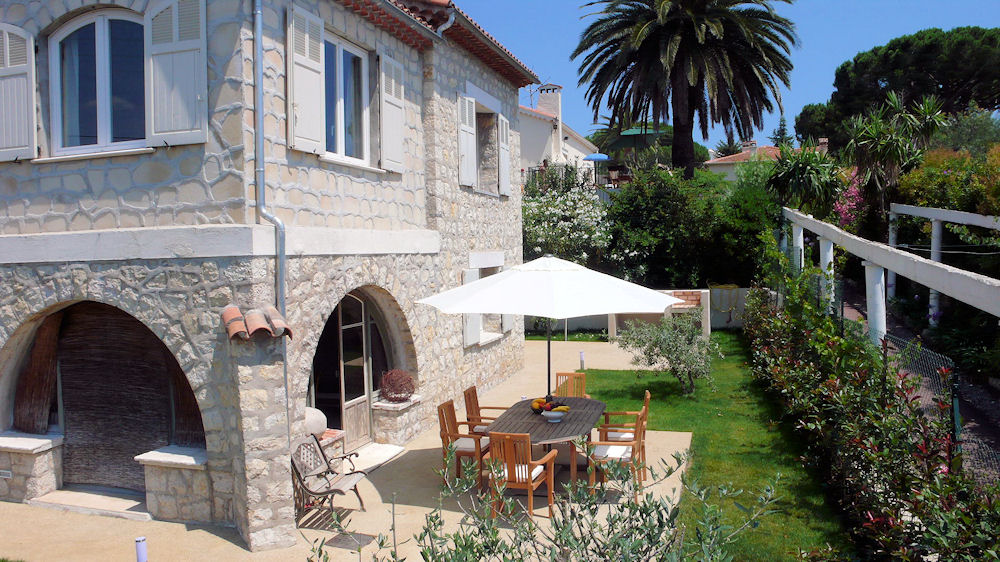 Villa Plein Soleil Juan les Pins vista desde el lado de piedra Villa de 2 plantas con mesa, sillas y sombrilla en el exterior