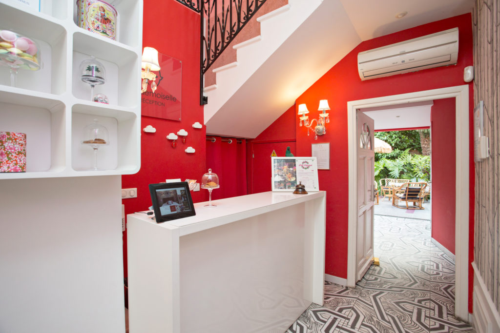 Vestíbulo del hotel Mademoiselle con paredes de color rojo brillante, decoración moderna y vista al jardín