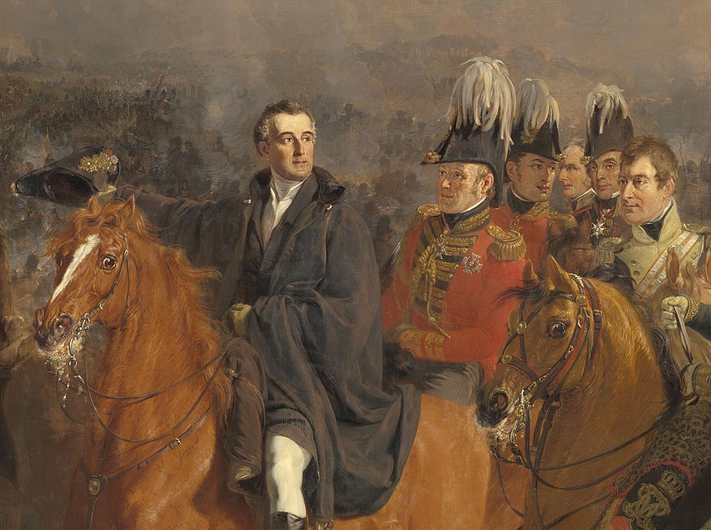 La batalla de Waterloo con Wellington sin sombrero, a caballo y un general de uniforme con sombreros detrás de él.