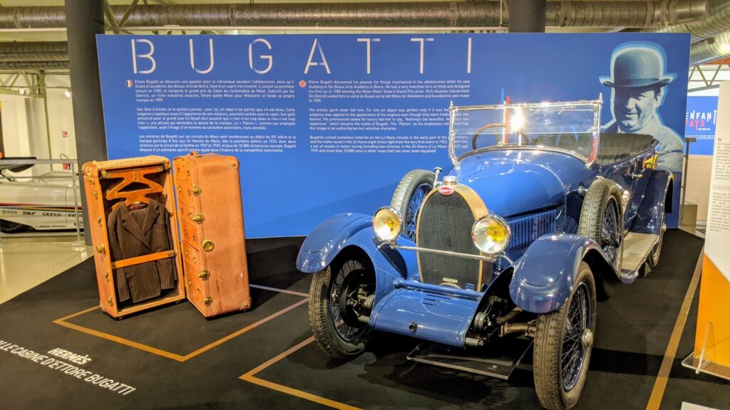 un coche bugatti azul en el museo de las 24 horas de Le Mans con un baúl Bugatti abierto al lado