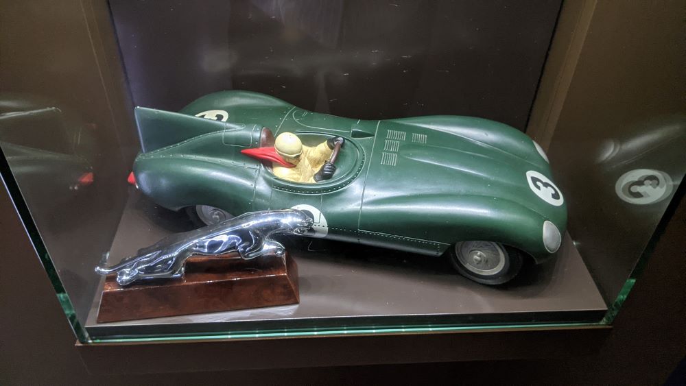 Un modelo elegante de un automóvil Jaguar verde con la figura al volante y el emblema de Jaguar en la parte delantera