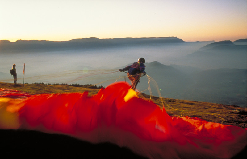 Hombre con gran equipo a la venta a punto de despegar en parapente en Chamrousse en Isere