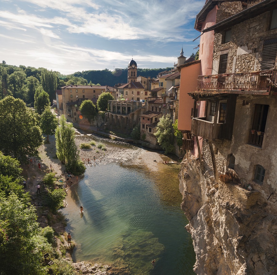 Pont en Royans en Isere mirando hacia el río en el centro, orillas boscosas a la izquierda y casas coloridas aferradas a las repisas en la orilla derecha