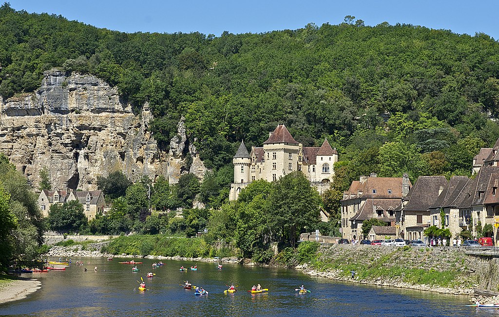 La Roque-Gageac mirando desde el otro lado del río mostrando el gran castillo blanco y el afloramiento rocoso a la izquierda