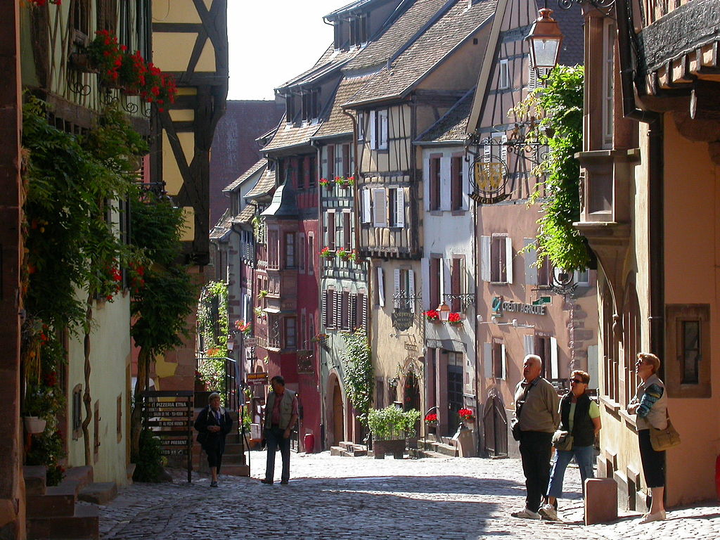 riquewihr en Alsacia. Una calle antigua con casas de entramado de madera y pintadas de vivos colores y gente caminando