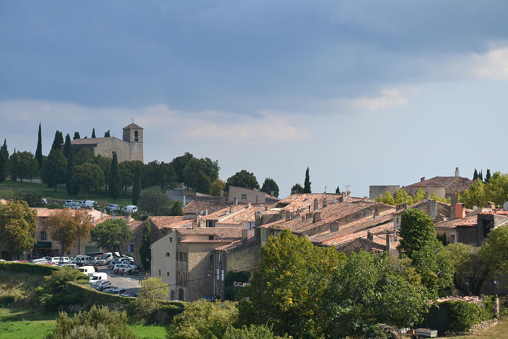 Tourtour en Provenza Vista general del pueblo con casas de piedra roja arraigadas y una torre de iglesia en la distancia. Muchos vegetales