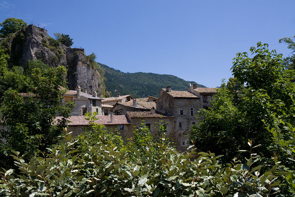 El pueblo de Chatillon-en-Diois estaba situado en lo alto de una montaña rocosa con rocas más altas detrás. Pueblo de antiguas casas de piedra, techos de tejas rojas y verdes en frente