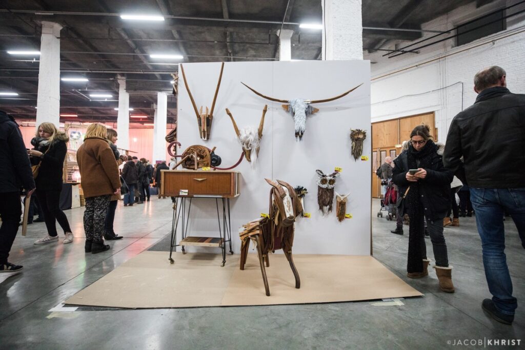 Roubaiz Braderie de l'Art con un stand que muestra extrañas esculturas de animales hechas con materiales reciclados, con la gente mirando