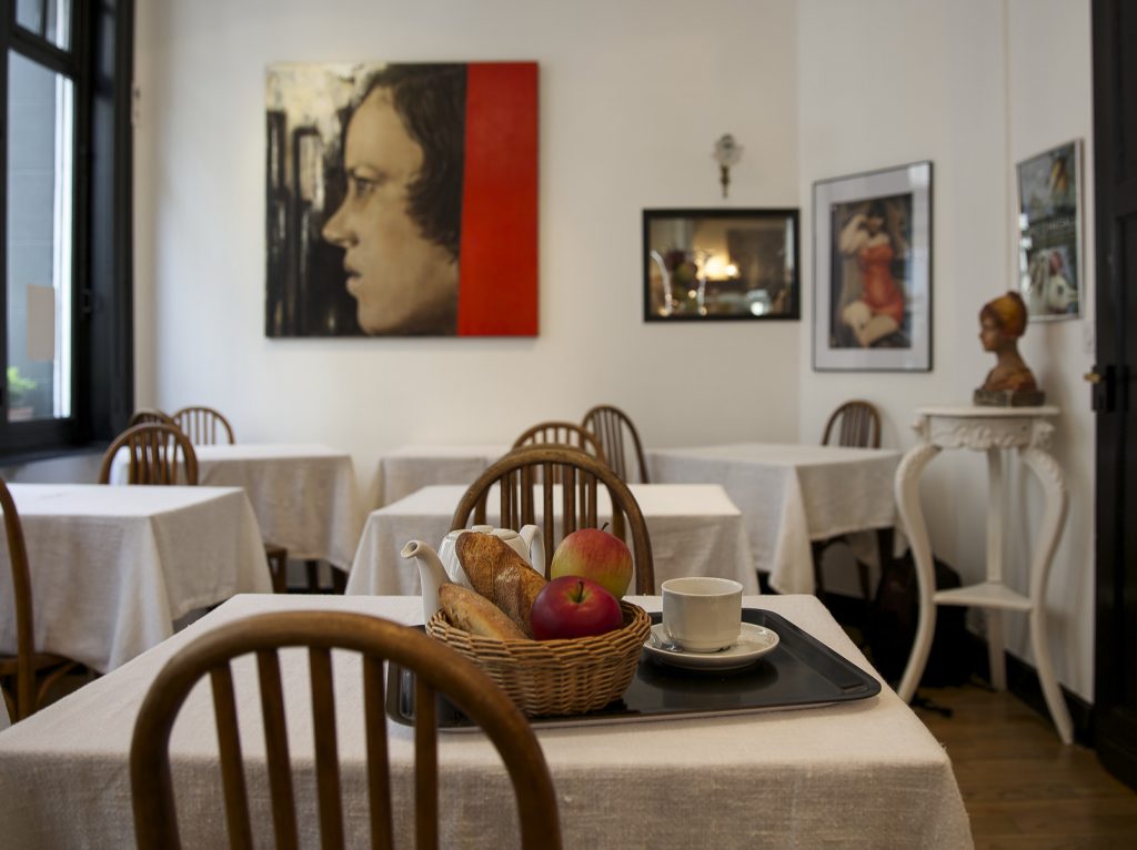 La sala de desayunos del Hotel Brueghal Lille con mesas de frutas y cuadros en las paredes