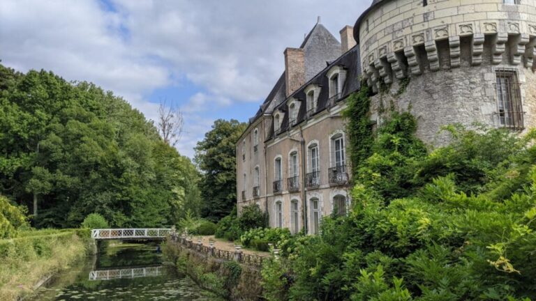 Castillo de Bazouges mirando hacia un foso a un puente con un castillo de piedra a un lado en el campo verde