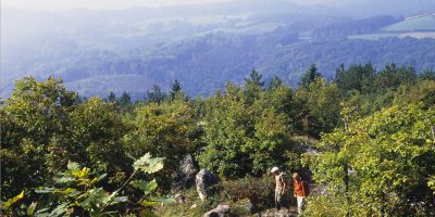 Caminantes por delante en la ladera de una colina con vistas al vasto paisaje de Morvan, Borgoña